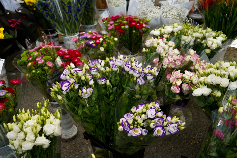 A vibrant display of fresh florist flowers arranged in bouquets, featuring a range of colours including purple and white eustoma, pink and red carnations, and white lisianthus. The flowers are individ